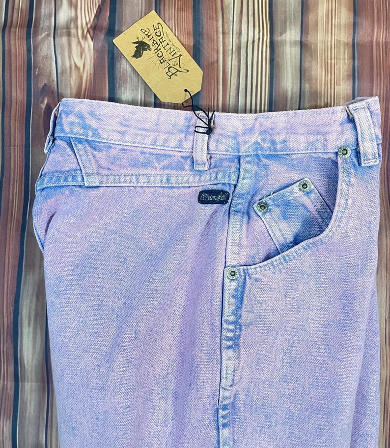 Pu&ograve; includere: Jeans Wrangler vintage lilla chiaro con lavaggio sbiadito. I jeans hanno un classico design a cinque tasche e una toppa con il logo Wrangler. &Egrave; attaccata un'etichetta Blackbird Vintage.