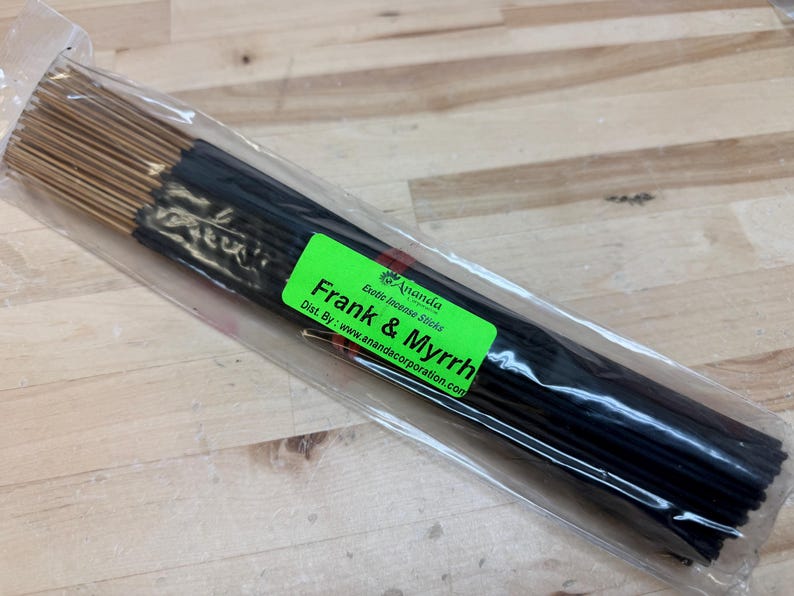 May include: A bundle of incense sticks in a clear plastic package. The sticks are black with gold tips. A green label reads "Frank & Myrrh" and "Ananda Exotic Incense Sticks."