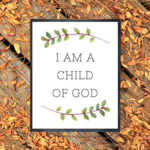 May include: A white printable sign with a black border and green watercolor leaves on the top and bottom. The sign says "I am a child of God".
