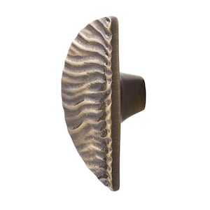 Peut inclure: Un bouton de porte en laiton antique de forme demi-ronde avec une surface texturée et ondulée.