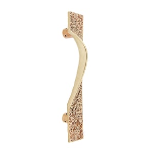May include: A gold-toned door handle with a textured surface and a curved design. The handle is attached to a square plate.