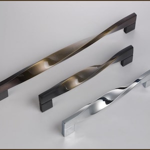 May include: Three cabinet door handles with a twisted design. The handles are made of metal and come in three finishes: antique brass, black, and chrome.