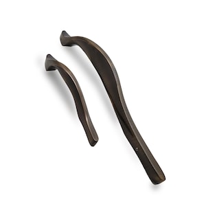 Puede incluir: Dos tiradores de armario de color bronce con un diseño curvo y ergonómico. Los tiradores son de diferentes tamaños, uno más grande y otro más pequeño, ambos con un acabado liso y pulido. Se encuentran sobre un fondo blanco.