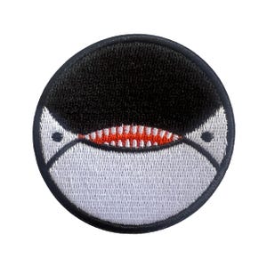 Puede incluir: Parche bordado circular con diseño de orca. La parte superior es negra, la inferior blanca, con boca roja y blanca. Borde negro. Ideal para personalizar ropa y accesorios.