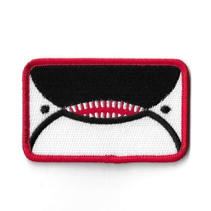 May include: A red, white, and black embroidered patch with a cartoon shark's open mouth.