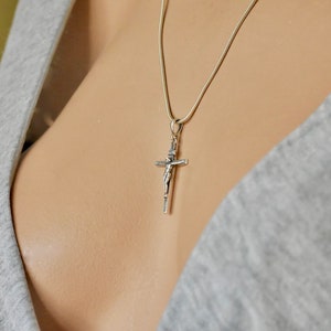 Puede incluir: Un collar de cadena de plata con un colgante de crucifijo de plata.