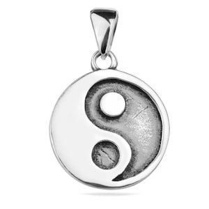 Puede incluir: Colgante de plata con un símbolo yin yang. El colgante es redondo y tiene una superficie texturizada.