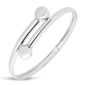 Può includere: Un braccialetto rigido in argento con due accenti rotondi. Il braccialetto è aperto e ha una chiusura a cerniera.