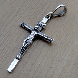 Puede incluir: Pendiente de cruz de plata con una figura detallada de Jesucristo y la inscripci&oacute;n "INRI" en la cruz.