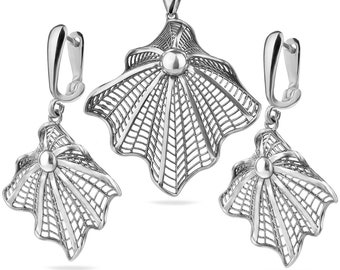 May include: A silver filigree pendant necklace and matching earrings set. The pendant and earrings are shaped like a stylized shell with a delicate, intricate design.