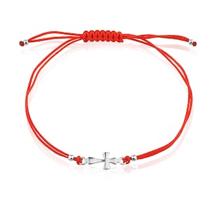 May include: Red string bracelet with a silver cross charm. The bracelet is adjustable and has a sliding knot closure.