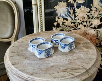 Puede incluir: Dos saleros dobles de cerámica blanca con diseños florales azules y blancos. Los saleros están sobre una superficie de madera clara.