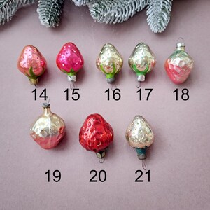 May include: A collection of vintage Christmas ornaments shaped like strawberries and other fruit. The ornaments are in various shades of red, pink, and gold, with green and silver accents. Each ornament has a small metal cap and a loop for hanging. Numbers 14-21 are visible.