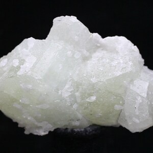 May include: A cluster of pale green fluorite crystals with a glassy luster. The crystals are intergrown and have a rough, textured surface.