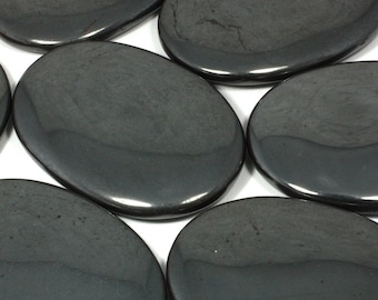 May include: A collection of six smooth, oval-shaped hematite stones. The stones are a dark gray color with a slightly metallic sheen.