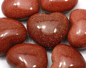 May include: Six heart-shaped polished red sandstone stones. The stones are smooth and have a sparkly, glittery texture.