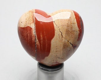 May include: A heart-shaped polished stone with red and white stripes. The stone is on a silver stand.