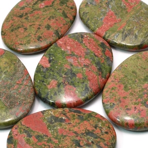 May include: Six smooth, oval-shaped stones with a mottled pattern of green, red, and black. The stones are polished and have a glossy finish.