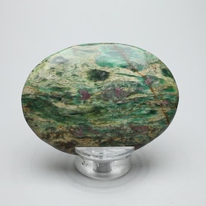 May include: A round, green and white cabochon with a swirling pattern of pink and brown inclusions. The cabochon is polished and has a smooth surface.