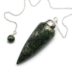 Könnte beinhalten: Grünes und weißes Steinpendel mit einer silbernen Kette und einer silbernen Spitze. Das Pendel ist tropfenförmig und hat ein wirbelndes Muster.