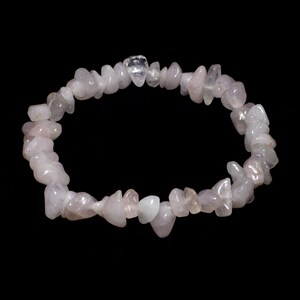 May include: A pink rose quartz chip bracelet made of natural stones. The bracelet is made of small, irregular shaped chips of rose quartz, strung together on a clear elastic cord.