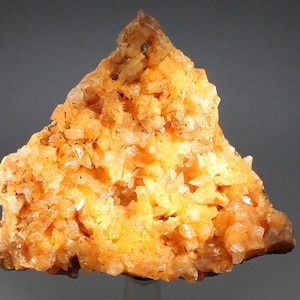May include: A large, triangular cluster of orange calcite crystals. The crystals are sharp and well-defined, with a glassy luster. The cluster is about 6 inches tall and 5 inches wide.