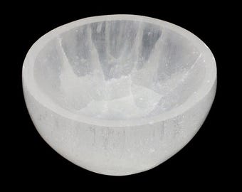 May include: A white selenite bowl with a smooth, polished surface. The bowl is round and has a slight lip around the edge. It is ideal for holding crystals, jewellery, or other small items.