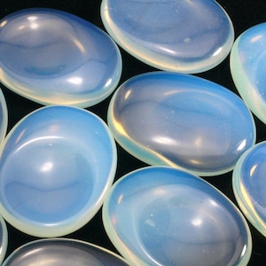 May include: A collection of smooth, oval-shaped, iridescent opalite stones. The stones are a pale blue colour with a white iridescent sheen.