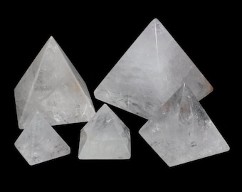 May include: A set of six clear quartz crystal pyramids of varying sizes. The pyramids are arranged in a cluster on a black background.