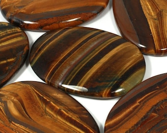 May include: Six smooth, oval-shaped tiger's eye stones with brown, gold, and black stripes. The stones are polished and have a glossy finish.