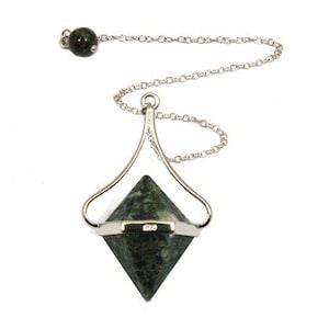May include: A pendulum featuring a green, pyramid-shaped stone hanging from a silver chain. The chain is attached to a silver frame and a small green bead. The stone has a speckled pattern and is designed for divination.