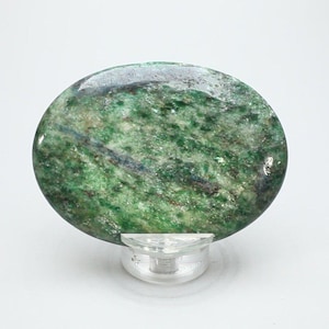 May include: A round, polished stone with a vibrant green hue, speckled with darker green and blue veins. The stone is displayed on a clear, plastic stand, showcasing its natural patterns and textures. The stone's surface has a glossy finish.