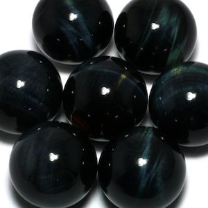 May include: Seven spherical gemstones, each with a polished, glossy black finish. The stones display swirling patterns of blue and green. The gemstones are arranged together, highlighting their smooth, reflective surfaces. The stones are likely around 2-3 cm in diameter.