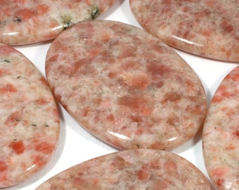 May include: Five smooth, oval-shaped sunstone stones with a light orange and white color. The stones have a natural, polished finish.