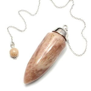 May include: A light brown crystal pendulum with a silver chain and a small bead at the end. The pendulum is shaped like a teardrop and has a smooth, polished surface.