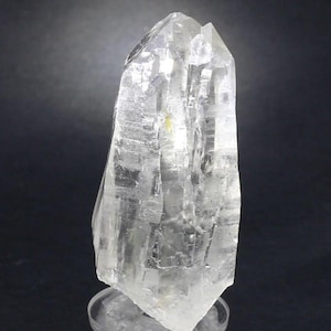 Puede incluir: Una taza de cerámica blanca con un asa negra y el texto "But First, Coffee" en negro y negrita. La taza está sobre una superficie blanca.