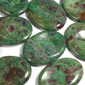 May include: A collection of oval-shaped green stones with red and brown flecks. The stones are smooth and polished.