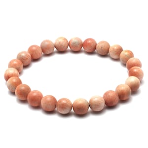 May include: A bracelet made of light orange sunstone beads. The beads are round and have a smooth, polished finish.