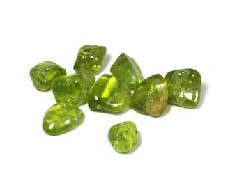 May include: A group of nine green peridot tumbled stones. The stones are smooth and polished, with a light green colour.