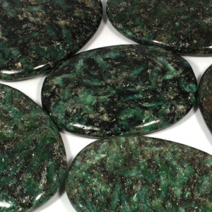 Pode incluir: Uma coleção de seis pedras lisas de forma oval, de cor verde e preta. As pedras têm um aspeto manchado, marmorizado.