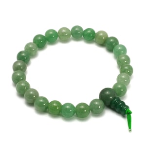 May include: A green gemstone mala bracelet with a green tassel. The bracelet is made of round beads and is strung on a thin cord.