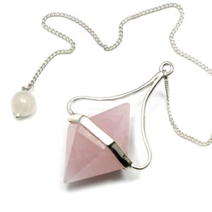 Può includere: Un pendolo di cristallo di quarzo rosa rosa con una catena d'argento e una piccola perla bianca all'estremità.