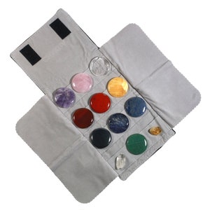 May include: A gray fabric pouch with a flap that opens to reveal 12 round, polished stones of various colors, including amethyst, rose quartz, red jasper, clear quartz, and green aventurine.