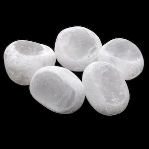 May include: Five smooth, white, oval-shaped stones. The stones are arranged in a cluster, with one stone in the center and the other four surrounding it.