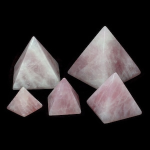 May include: Set of five pink rose quartz crystal pyramids of varying sizes. The pyramids are smooth and polished, with a light pink colour.