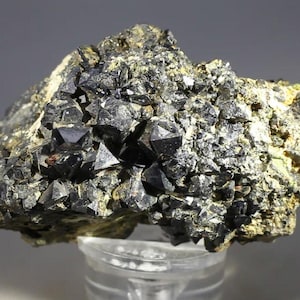 Może przedstawiać: Zestaw trzech ceramicznych kubków z nakrapianym, matowym wykończeniem. Kubki są w odcieniach kremu, jasnoszarym i ciemnoszarym. Każdy kubek ma prosty, minimalistyczny design i zaokrąglony uchwyt.