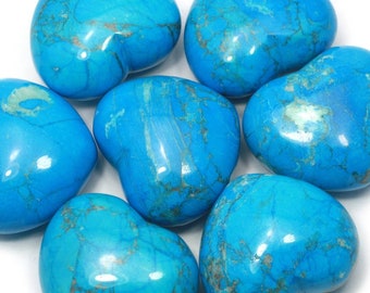 May include: Seven heart-shaped turquoise stones, each with a unique pattern of veining, are arranged on a white surface.