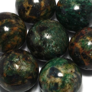 May include: A collection of seven green, black, and brown polished tumbled stones. The stones are round and have a smooth, polished surface.