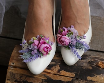 May include: White satin bridal shoes with lavender and pink floral embellishments.