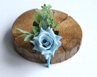 Puede incluir: Una rosa azul claro con hojas verdes, dispuesta sobre una rodaja de madera.